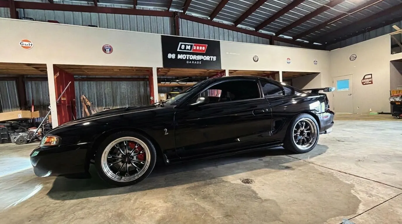 Mecánico trabajando bajo el capó de un Mustang